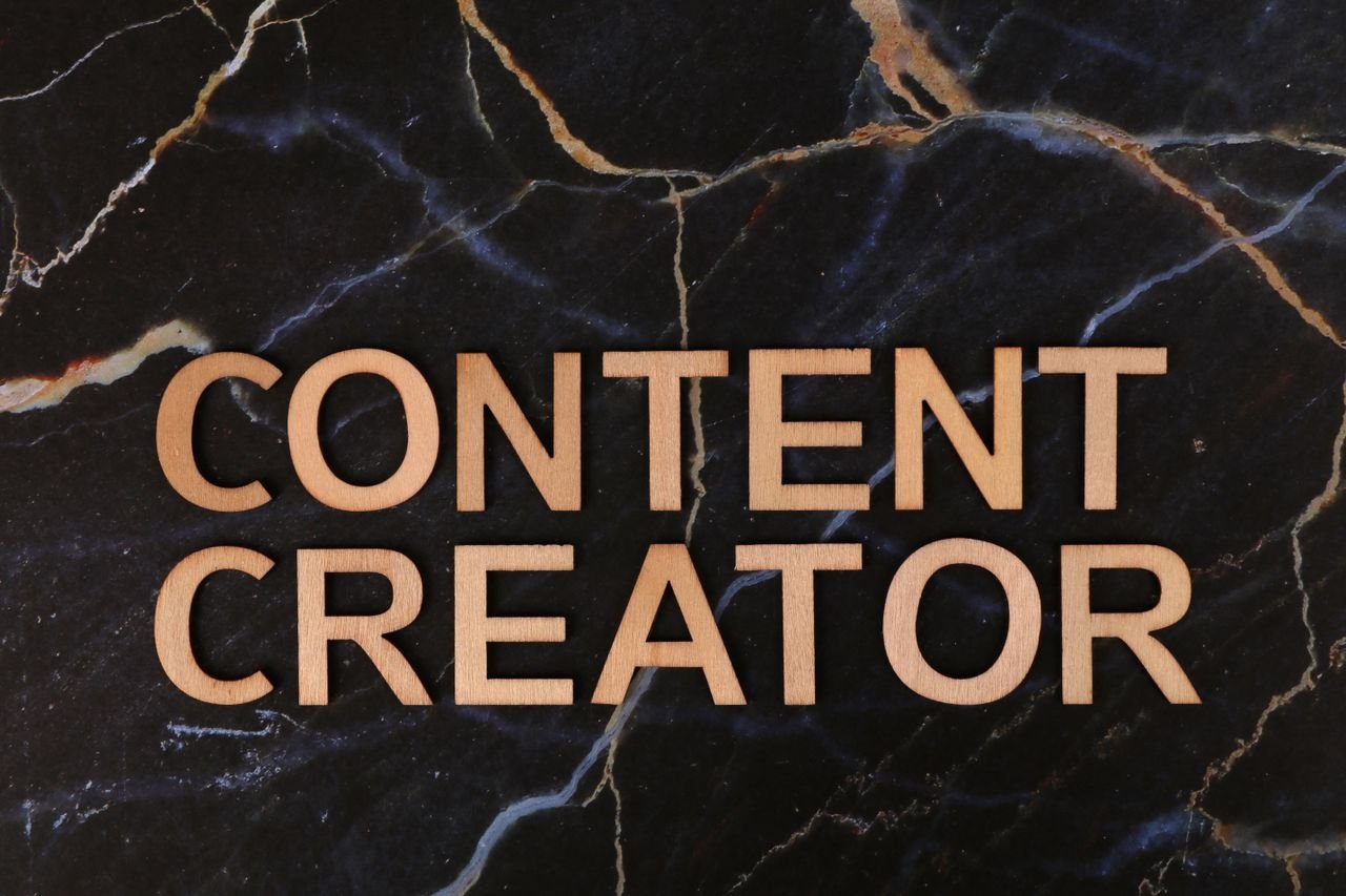 7 Digital Marketing Strategies for Small Businesses Wooden letters spelling 'CONTENT CREATOR' on a dark marble background.