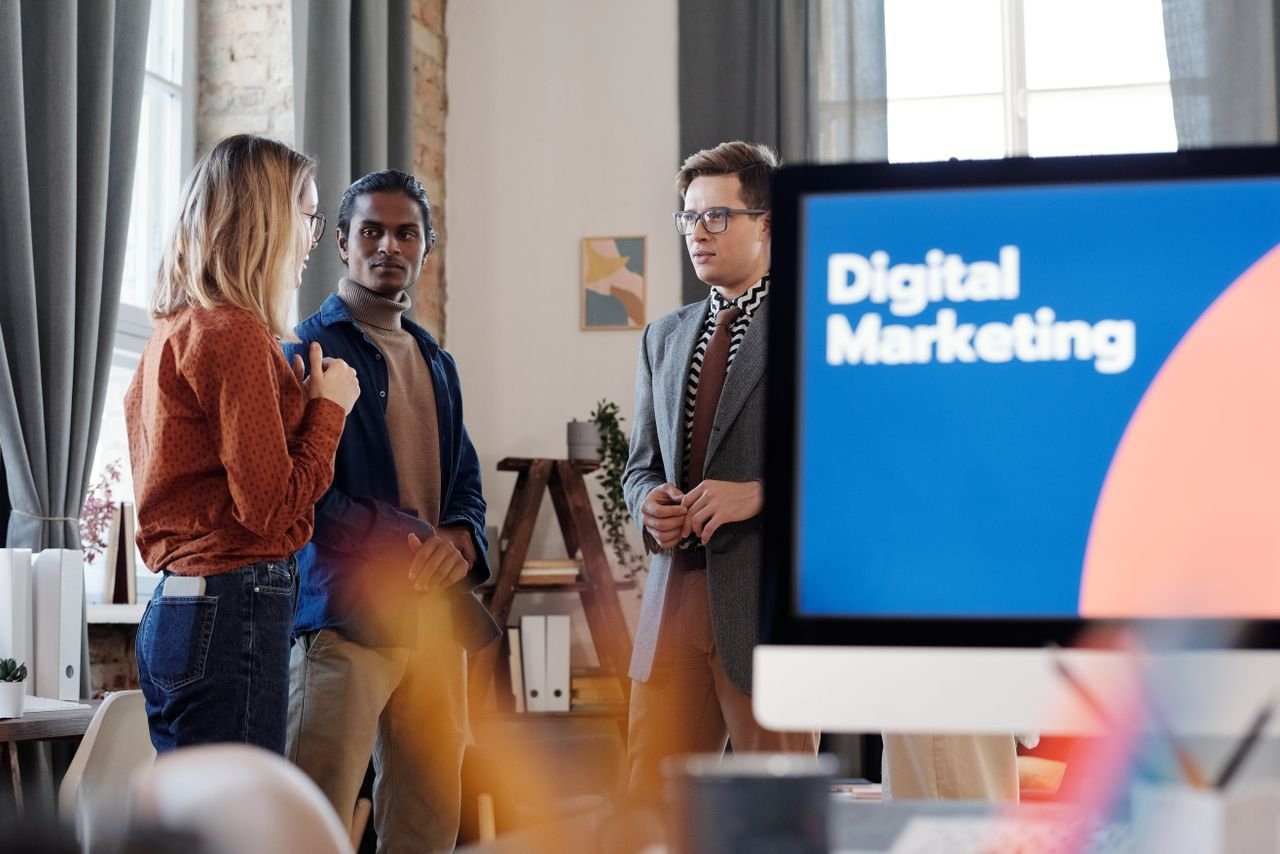 10 Social Media Marketing Mistakes to Avoid Group of colleagues discussing digital marketing strategies in an office setting.