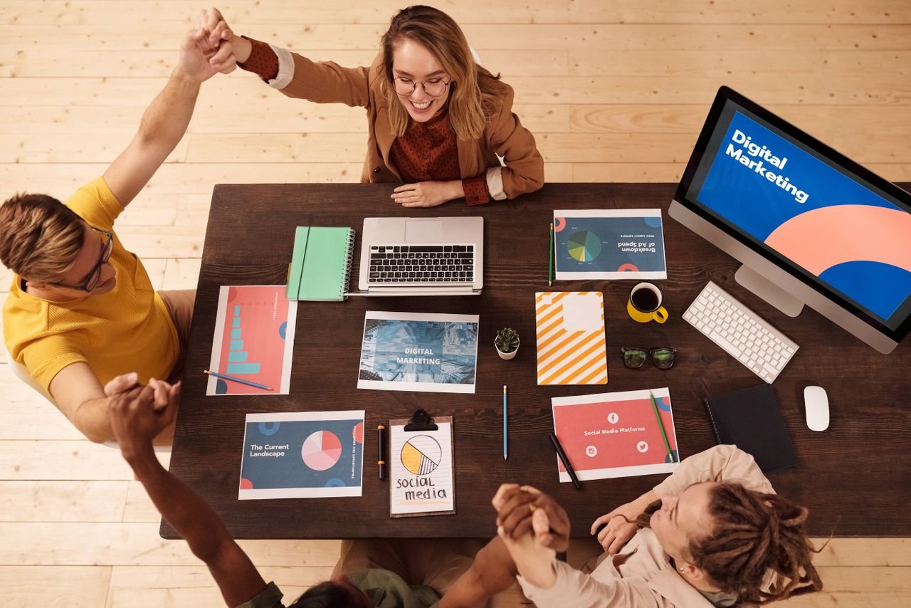 SEO vs Google Ads: Which Is Better? Colleagues celebrating success in a modern digital marketing office with teamwork and collaboration.